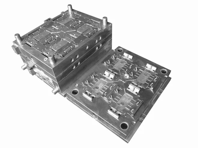A metal injection mold with intricate cavities and alignment pins is shown, with one half standing upright and the other lying flat, designed for manufacturing parts.